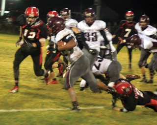 Mason Dalgliesh hangs on at the ankle to tackle a Kamiah runner. Tanner Ross, 12, is moving in to help. Rhett Schlader, 7, can be seen in the background.