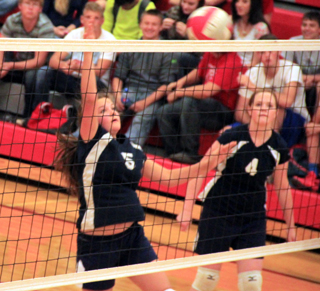 Taylor Lustig spikes the ball at C.V. as Bridget Beckman looks on.