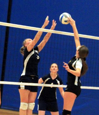 Ally Sonnen puts up a block against Highland at District as Bridget Beckman looks on.
