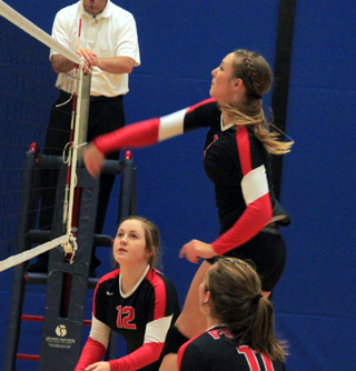 Mykaela McWilliams spikes the ball against Lapwai at District. Also shown are Angela Wemhoff and Krystin Uhlenkott.