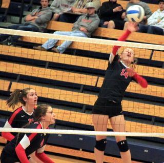 Sarah Seubert spikes the ball as Krystin Uhlenkott and Shayla VonBargen look on.