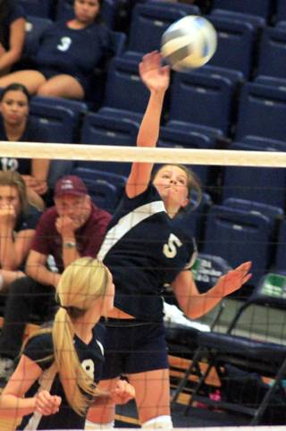 Taylor Lustig spikes the ball. Also shown is Lauren Stubbers.