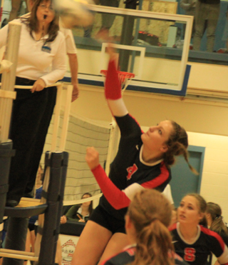 Shayla VonBargen spikes the ball against. Oakley. Also shown are Sarah Seubert and Hailey Danly.