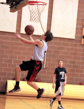 Brandon Anderson tries a reverse lay-up as Brandon Higgins watches during Mondays boys varsity practice.