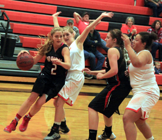Kylie Tidwell drives past a Troy player while Shayla VonBargen blocks off another defender.