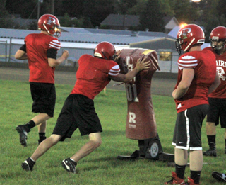 A lineman hits the sled during football practice.
