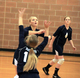 Lexi Currier, back to camera, has just set the ball and Ally Sonnen  gets ready to go up for the kill as Bridget Beckman, 4, watches.