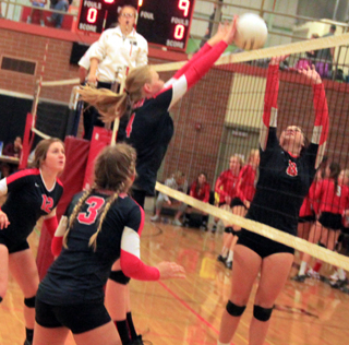 Leah Higgins makes a block against Asotin. Also shown are Angela Wemhoff and Chaye Uptmor.