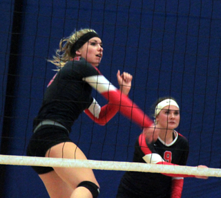 Chaye Uptmor slams the ball over against Genesee. At right is Sydney Bruner.