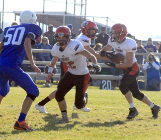 Luke Wemhoff takes a handoff from Devin Ross as Brandon Anderson gets ready to block #50 for Notus.