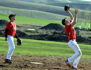Jake Stubbers battles the sun going after a pop fly at Genesee as Owen Anderson watches.