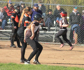 Kodie Tidwell with an RBI single at Kendrick. Noelle Uhlenkott can be seen scoring in the background.
