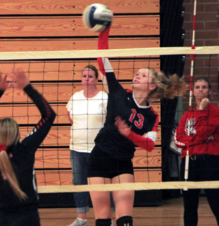 Theresa Wemhoff spikes the ball against Clarkston at the Border Battle as coach Julie Schumacher looks on.