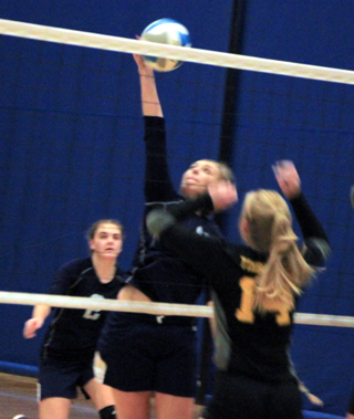 Kayla Rehder spikes the ball against Timberline at District. Also shown is Jade Prigge.
