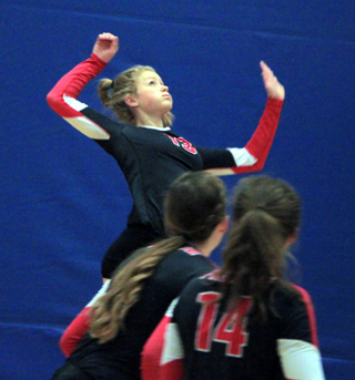 Theresa Wemhoff winds up for a spike at District against C.V. Also shown are Alexis Hiler and Kristyna Krogh.