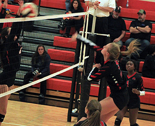 Ellea Uhlenkott pounds the ball between two Troy blockers as Madison Shears and Jade Prigge look on.