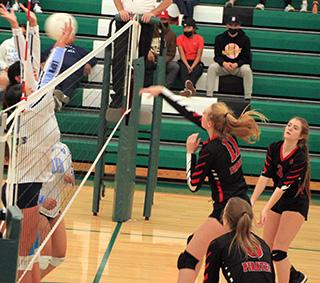 Alli Geis spikes the ball against Lapwai at District. Also shown are Tara Schlader and Delanie Lockett.