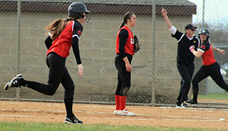 Coach Jeff Martin can be seen sending Mackenzie Key home as Tara Schlader heads for second with a double against Garfield-Palouse.