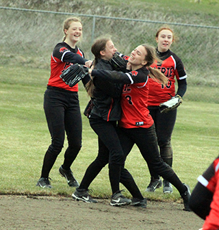 Everyone wants to celebrate with Ember Martin after she made the catch to end the first game against Genesee. From left are Laney Formsan, Martin, Delanie Lockett and Riley Enneking.