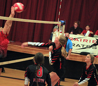 Alli Geis spikes the ball against C.V. as Julia Rehder and Lexi Schumacher get ready to play defense.
