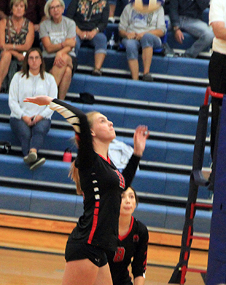 Alli Geis goes up for a spike at Genesee as Julia Rehder prespares to play defense.