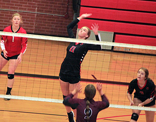 Alli Geis goes for a spike against Kamiah. Also shown are Kristin Wemhoff and Tara Schlader.