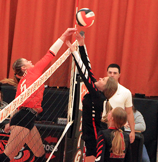 Lexi Schumacher tries to block a Kendrick hitter at the net. Also shown is Alli Geis.