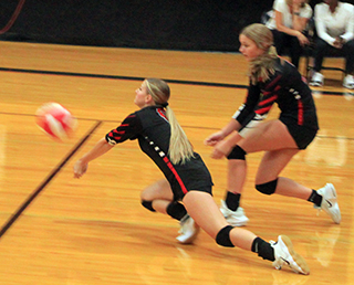 Sierra Oliver digs a Troy serve as Lexi Schumacher looks on.