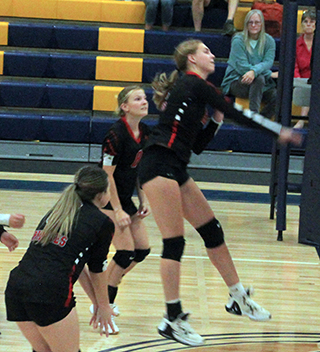 Alli Geis spikes the ball at Logos. Also shown are Tamden Pecarovich and Sierra Oliver.